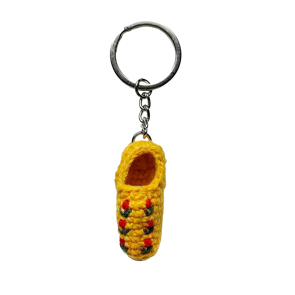 Yellow crocheted clog keyring with red and green accents on a white background