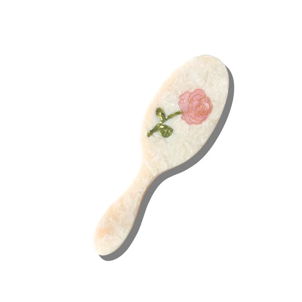 cream hairbrush with rose detail on a white background