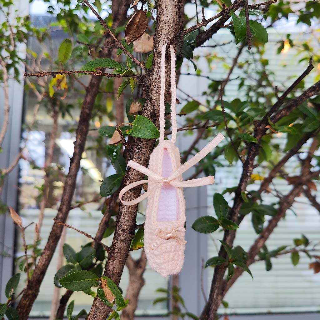 miniature crocheted ballet pointe shoe decoration on a tree branch