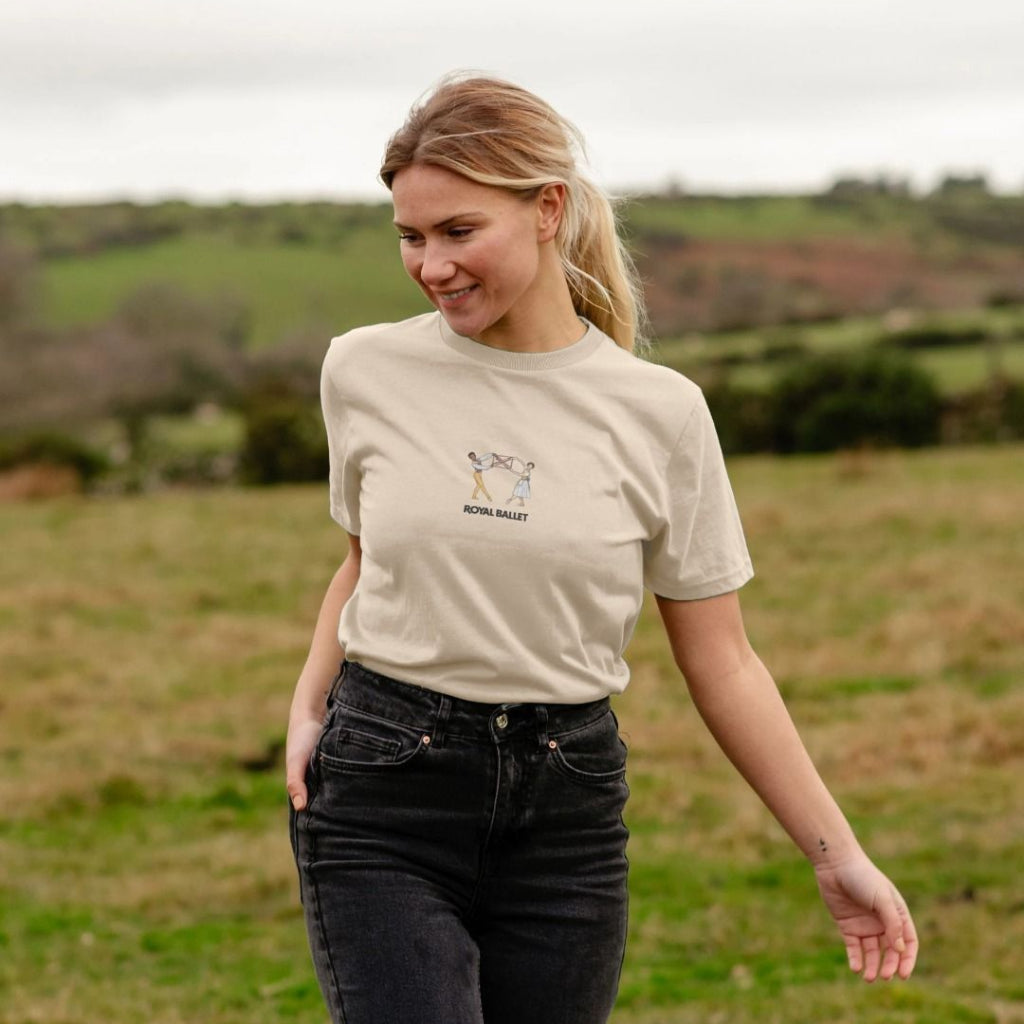Woman wearing a oat coloured t-shirt with a ballet design in a field