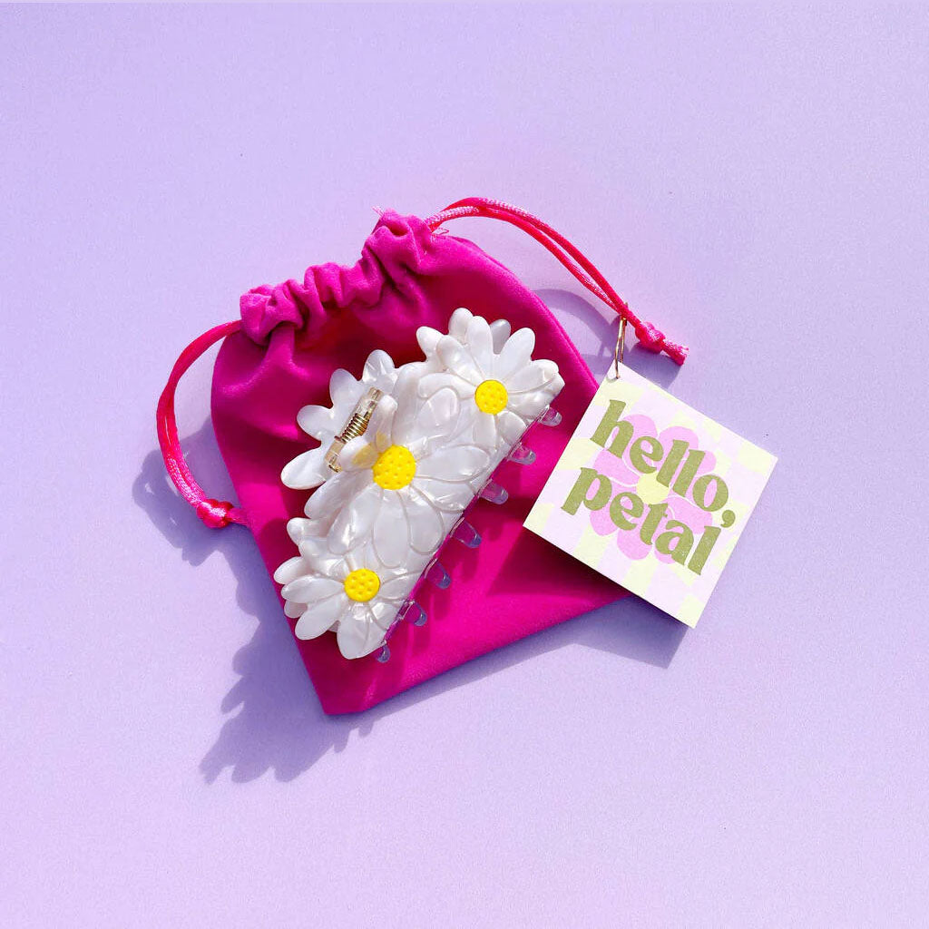 Daisy hair clip with pink drawstring bag and 'hello petal' tag on purple background