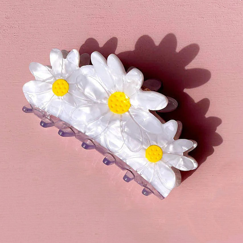 Set of three white daisies flower hair clips with yellow centres on a white background