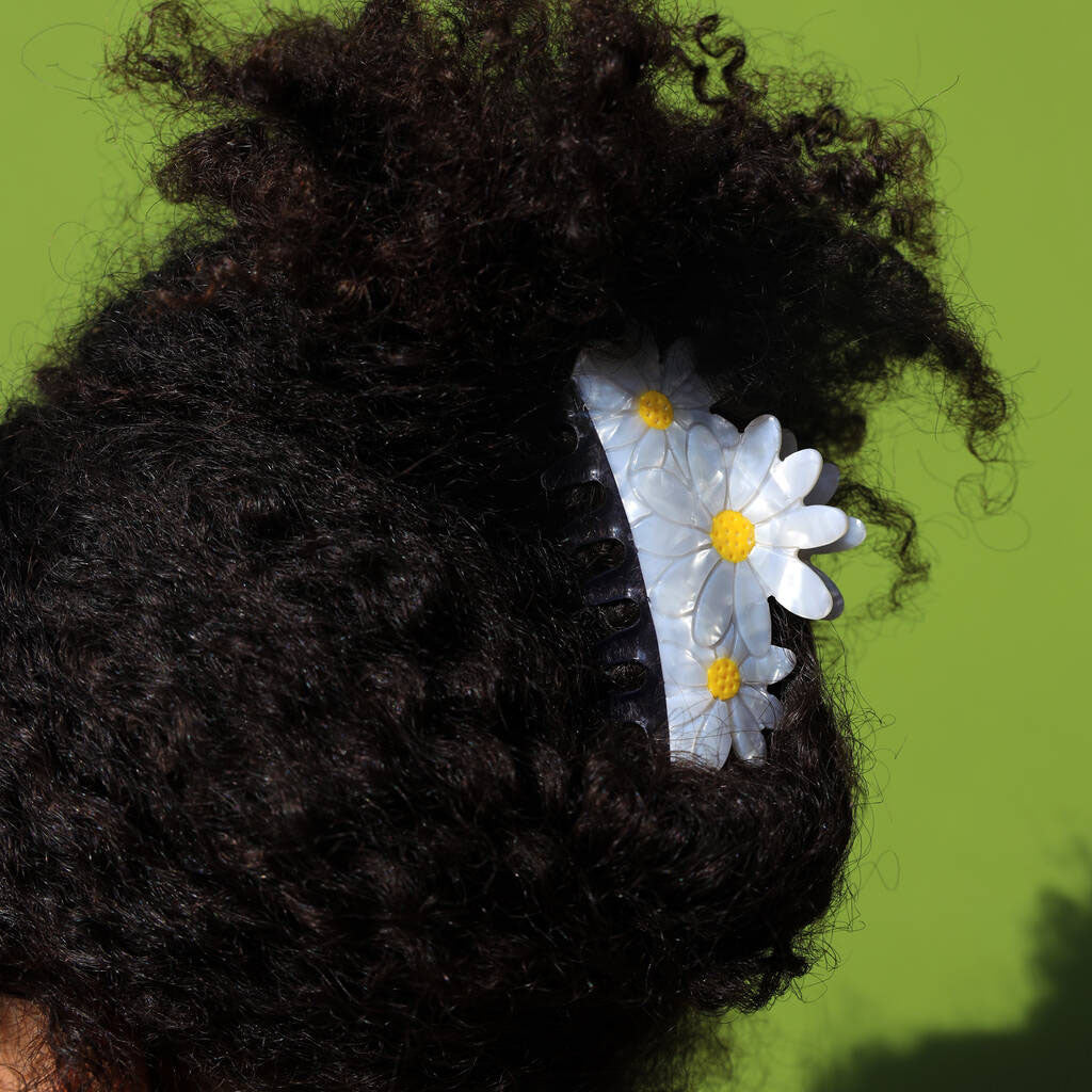 Close-up of a person's hair with  Daisy Hair Clip against a green background