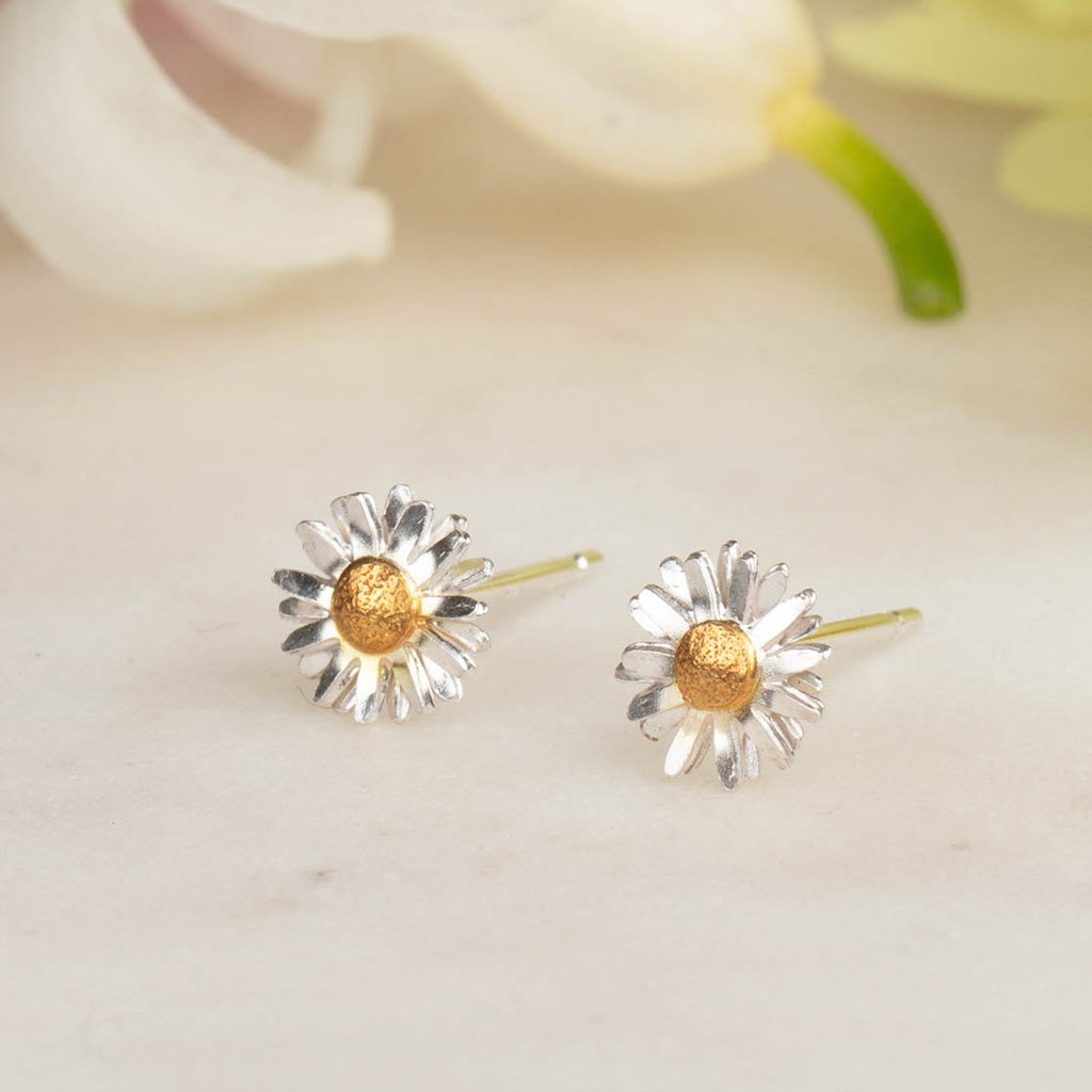 silver and gold daisy stud earrings on a white background