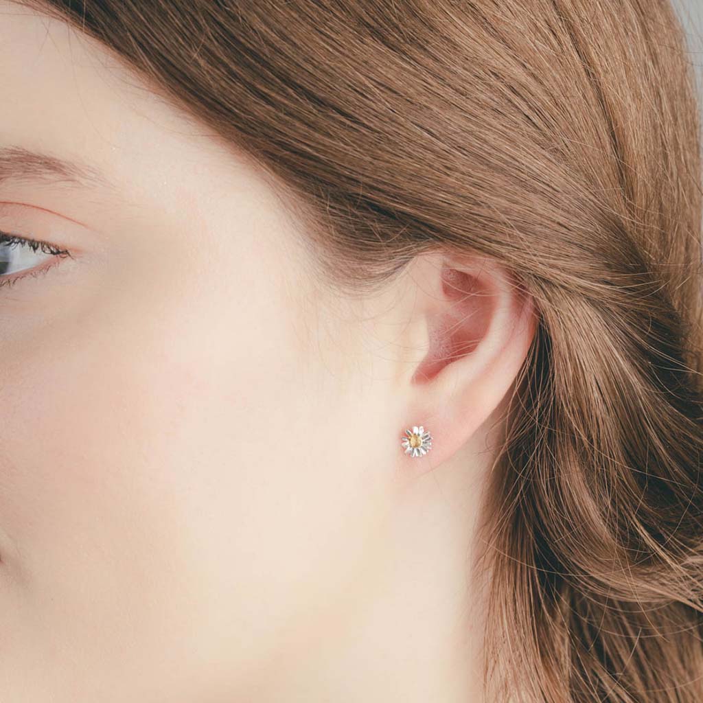 Close-up of a person wearing a daisy stud earring 