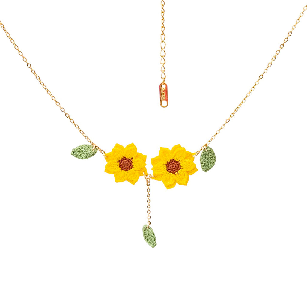 Two crochet sunflower pendants on a gold necklace on a white background
