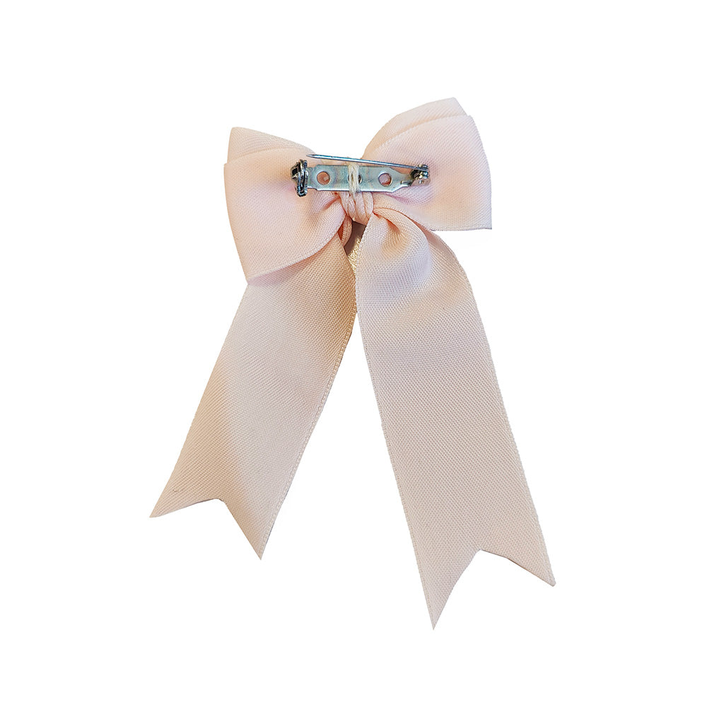 The back view of a pale blush pink satin bow brooch with a silver-toned metal clasp, shown against a solid white background.