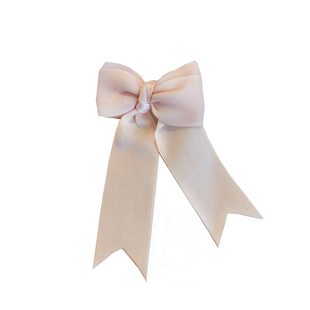 A light pink-beige satin ribbon bow brooch with two long tails, photographed against a solid white background.