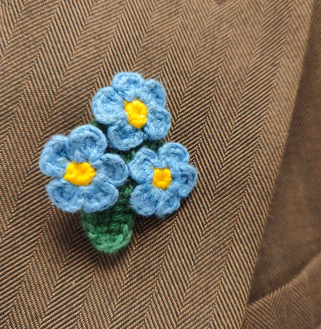 colourful crochet flower brooch on a white background