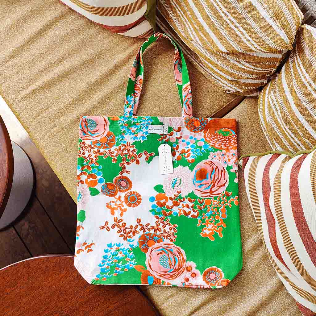 Floral tote bag on a wooden surface with striped cushions in the background