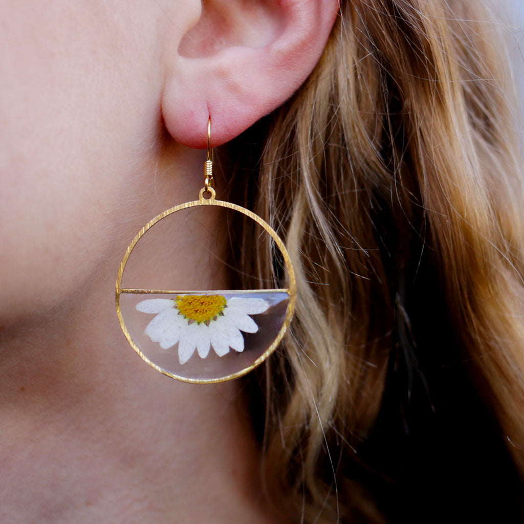 Gold hoop earrings with daisy flowers on a white background