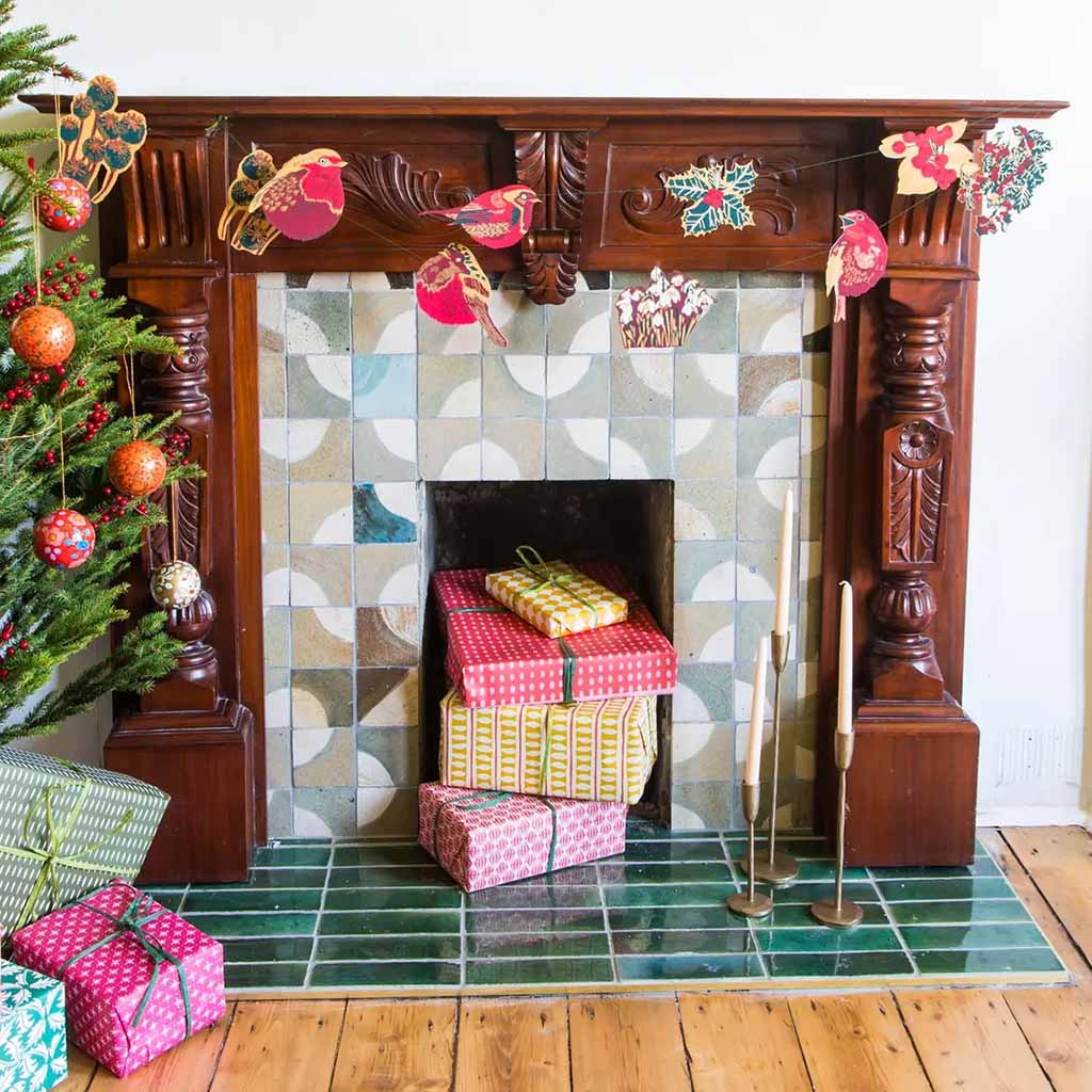 The Hedgerow paper garland on a fireplace next to a Christmas Tree and presents