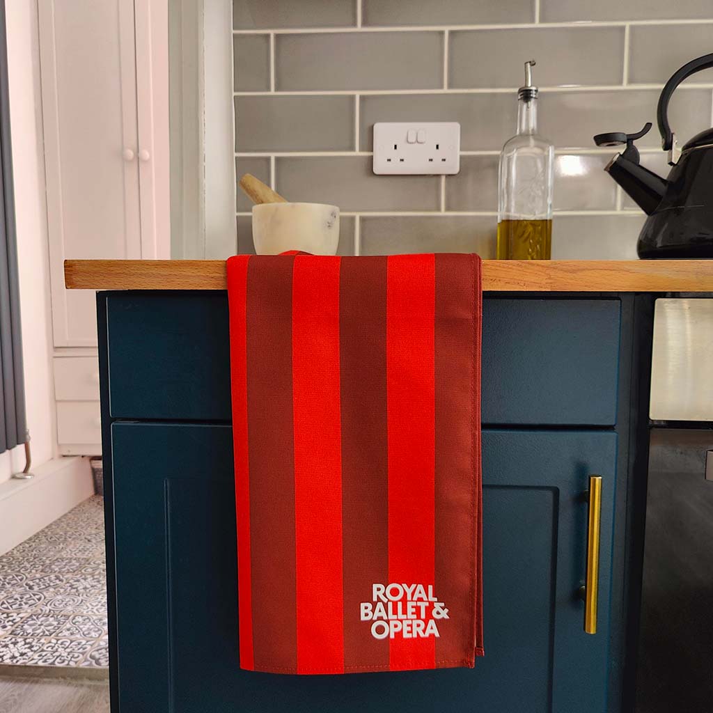 Red and brown RBO striped tea towel with 'Royal Ballet & Opera' branding on a white background