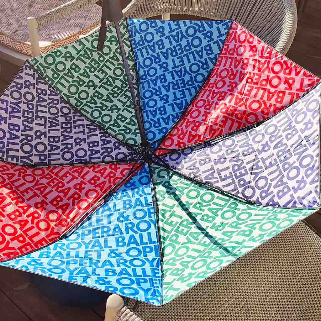 Inside umbrella with 'Royal Ballet &amp; Opera' colourful text pattern on a chair.