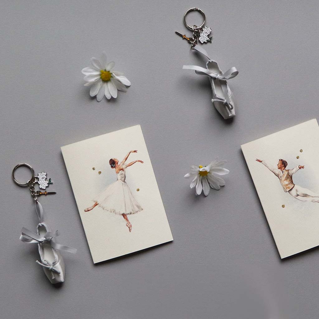 Giselle ballet shoe keyrings and cards on a gray surface with daisies.
