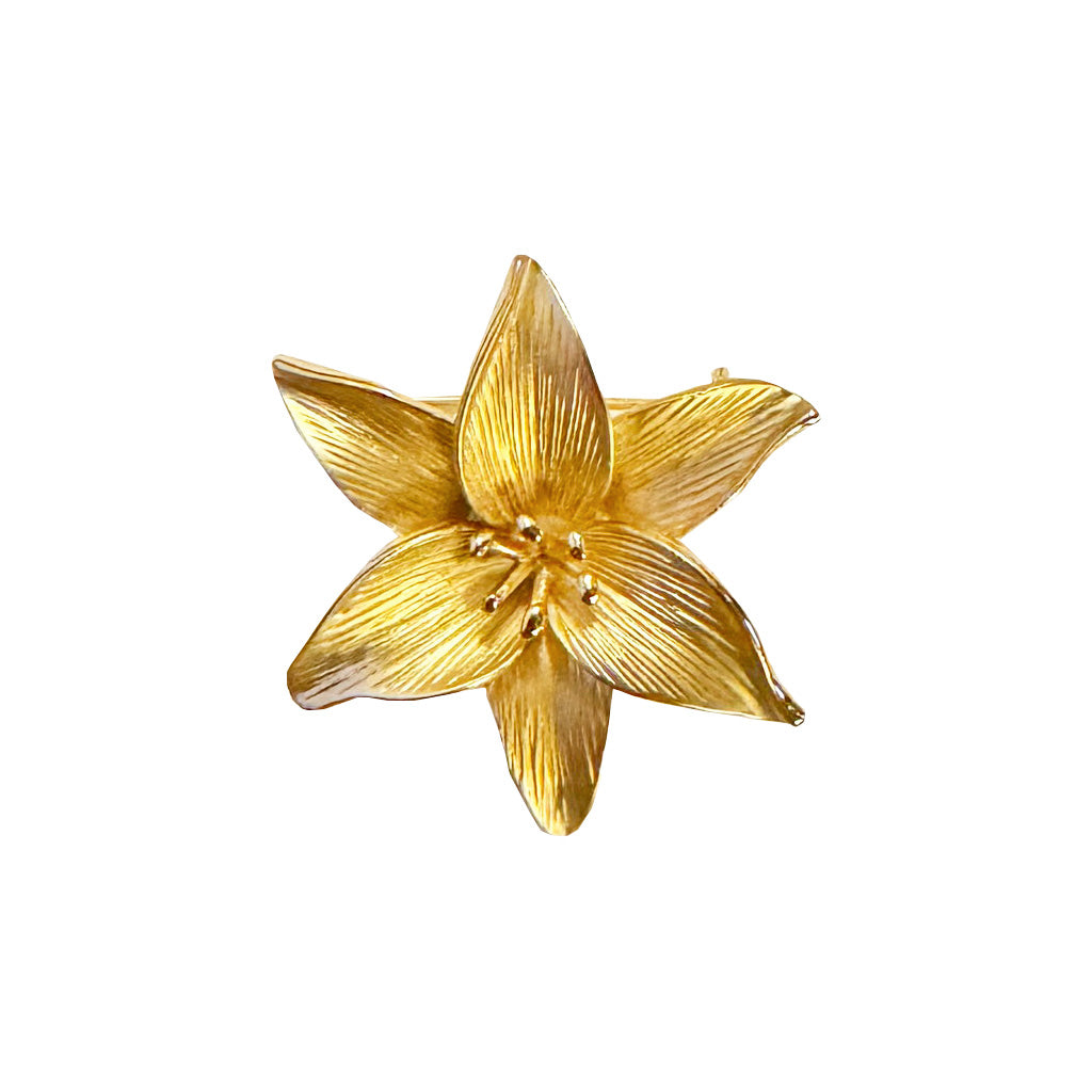 gold plated brooch of a lily on a white background