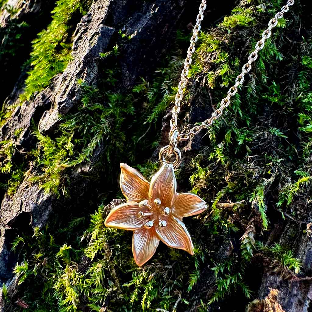 Gold necklace with a lily pendant on a white background