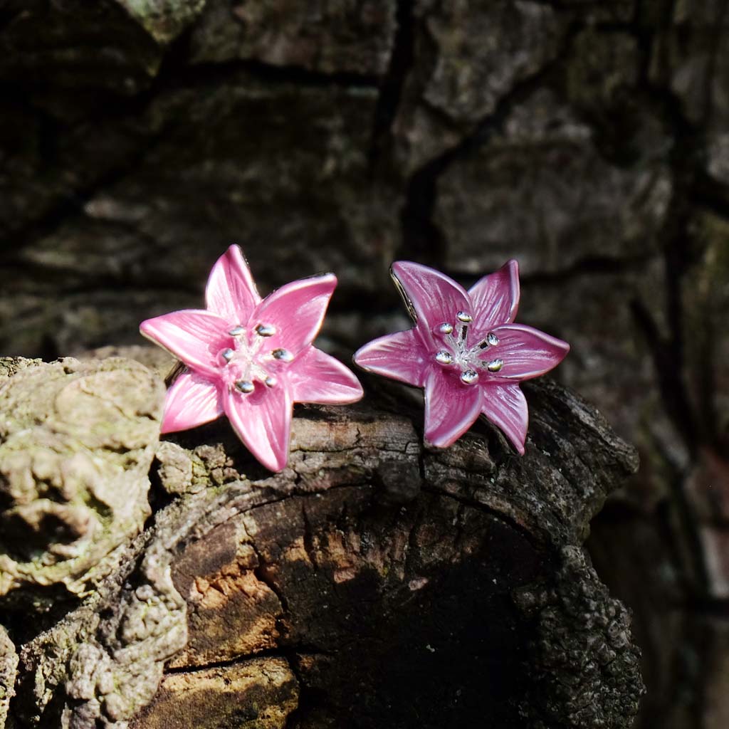 Pink flower-shaped earrings on a wooden surface