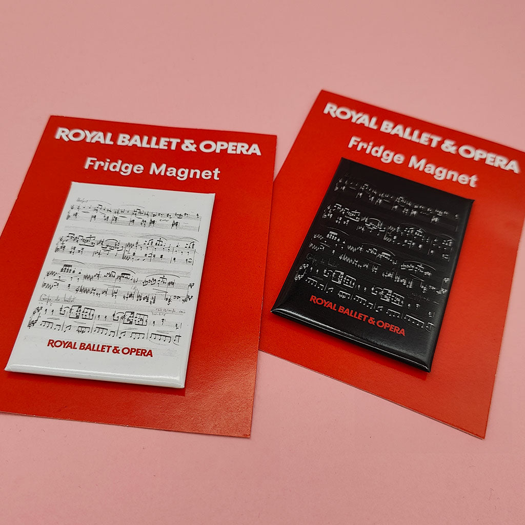Two Royal Ballet &amp; Opera fridge magnets displayed on red backing cards against a solid pink background. One magnet is white with black musical notation, and the other is black with white musical notation.