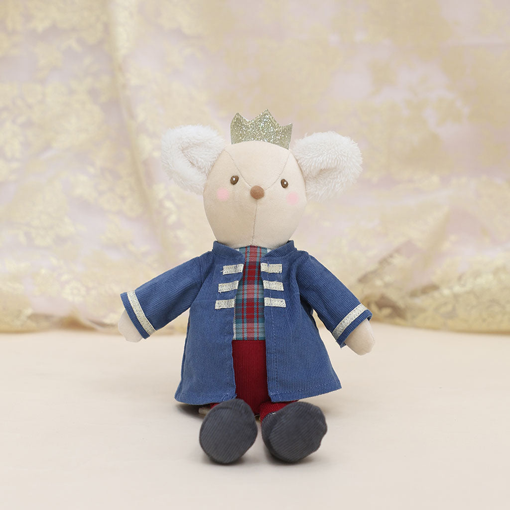 A plush mouse king doll wearing a blue jacket, red plaid shirt, red trousers, and a small glittery crown, posed against a soft beige lace backdrop.