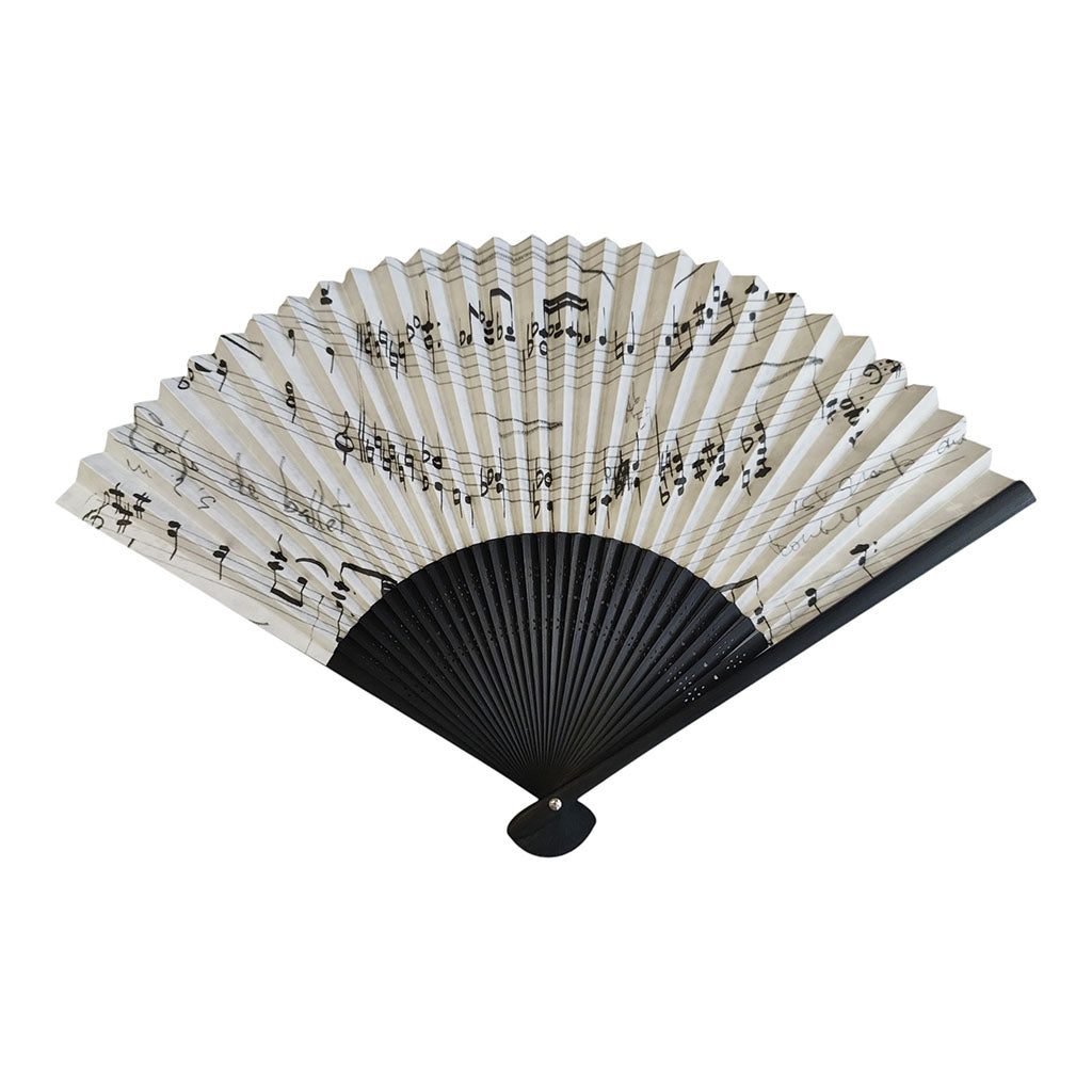 The reverse of the Music Manuscript  hand fan with a black ribbed frame and white paper panels printed with black musical notes and staff lines, shown open on a plain white background.