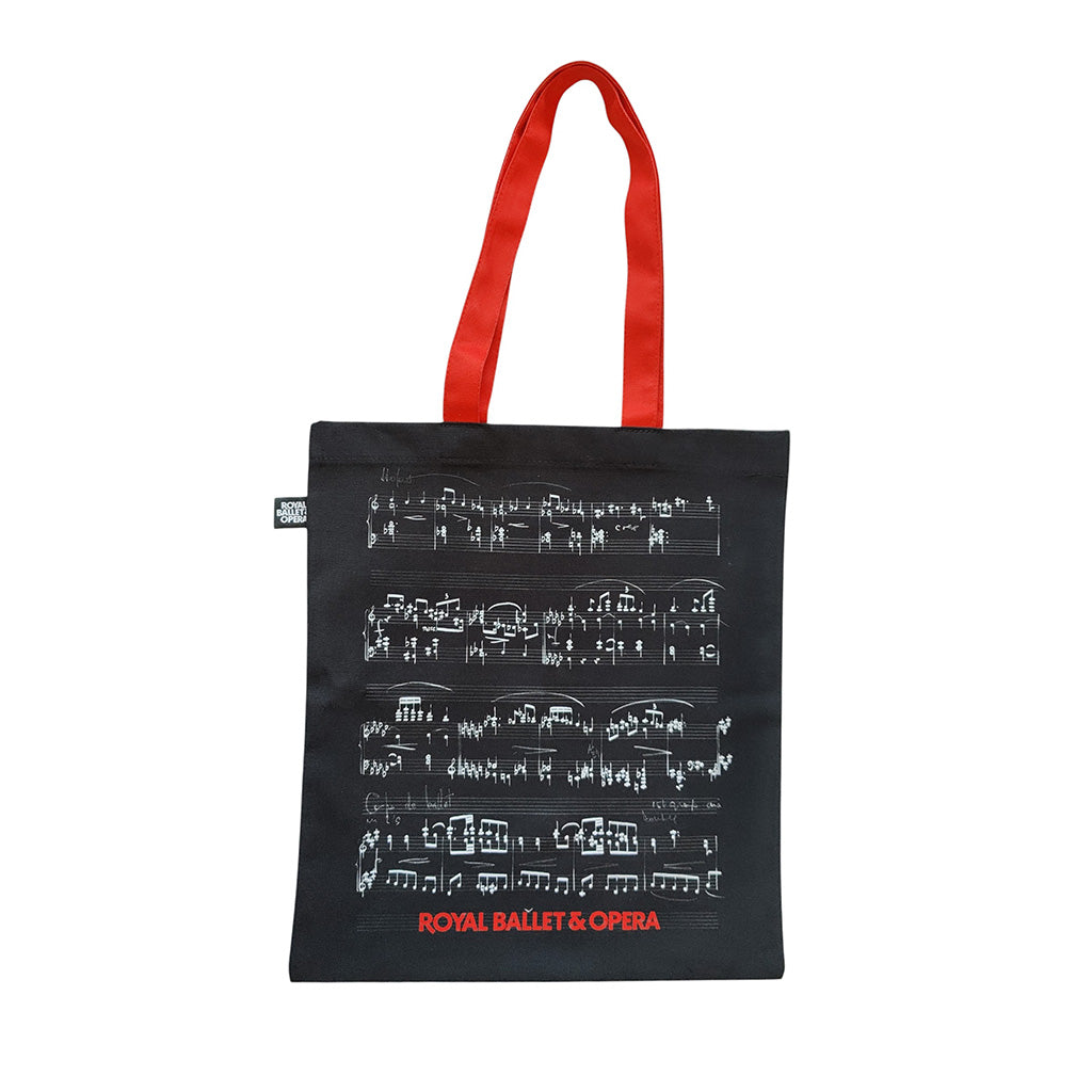 Black tote bag with musical notes and 'Royal Ballet &amp; Opera' text, red handle on white background