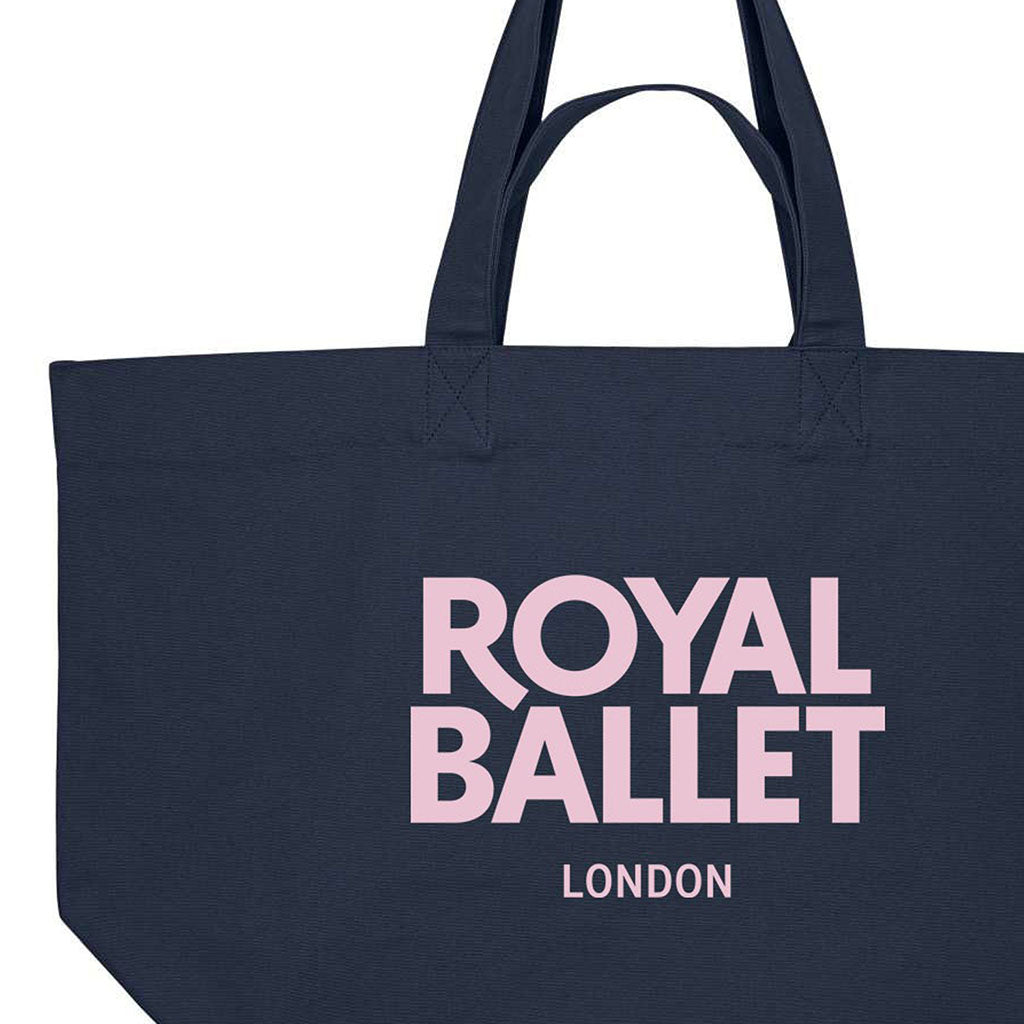 close-up of a navy shopper bag with pink text 'Royal Ballet London' on a white background