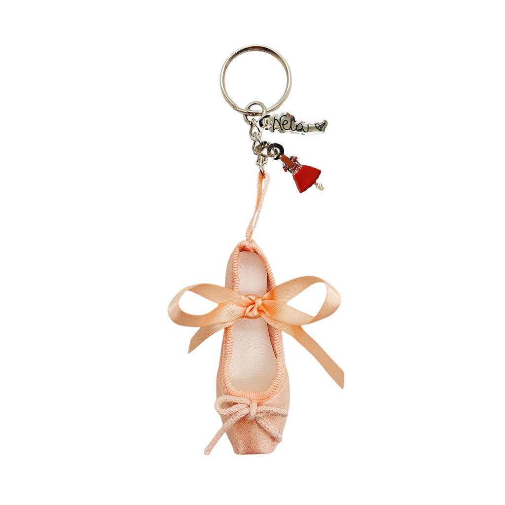 Pink ballet shoe keyring with Marianela Nunez charms on a white background