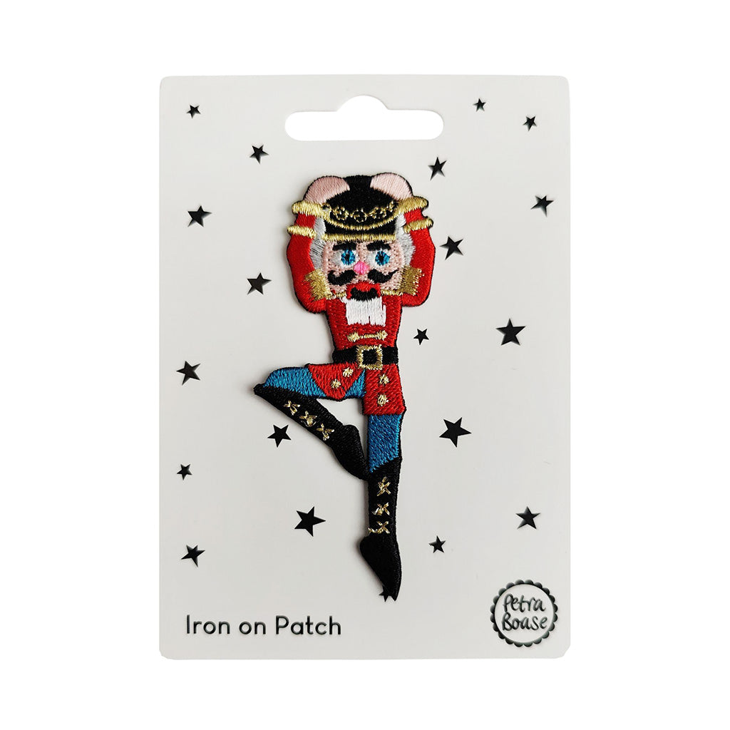 Iron-on patch of a Nutcracker character on a white card with star decorations, brand &#39;Petra Boase&#39; visible.