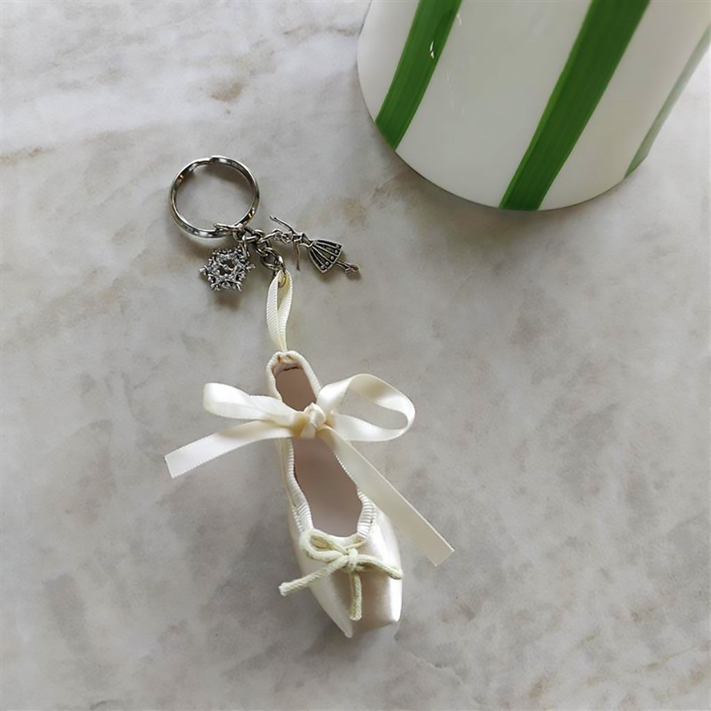 Limited Edition ballet Shoe Keying in light gold with clara and snowflake charms on a marble surface