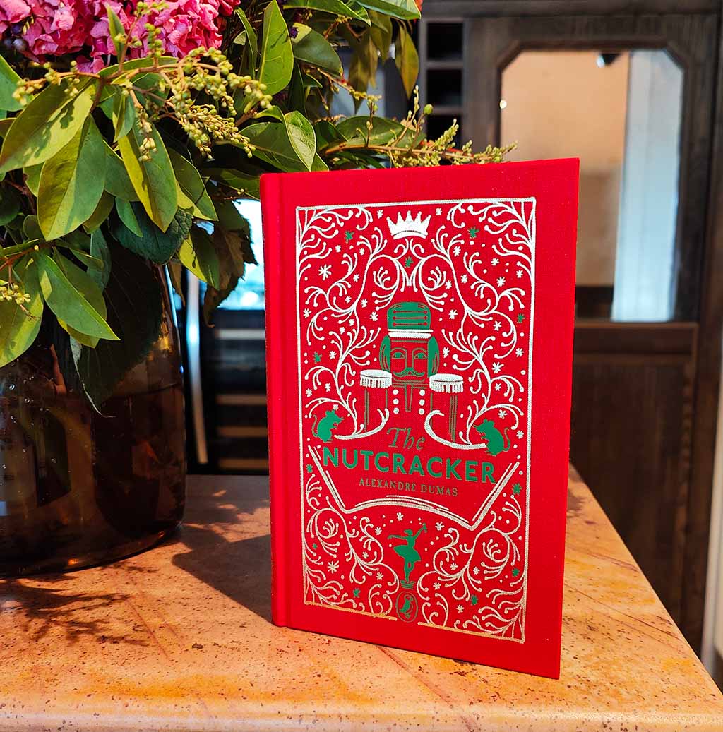 Decorative book cover of 'The Nutcracker' with red and gold design on a white background