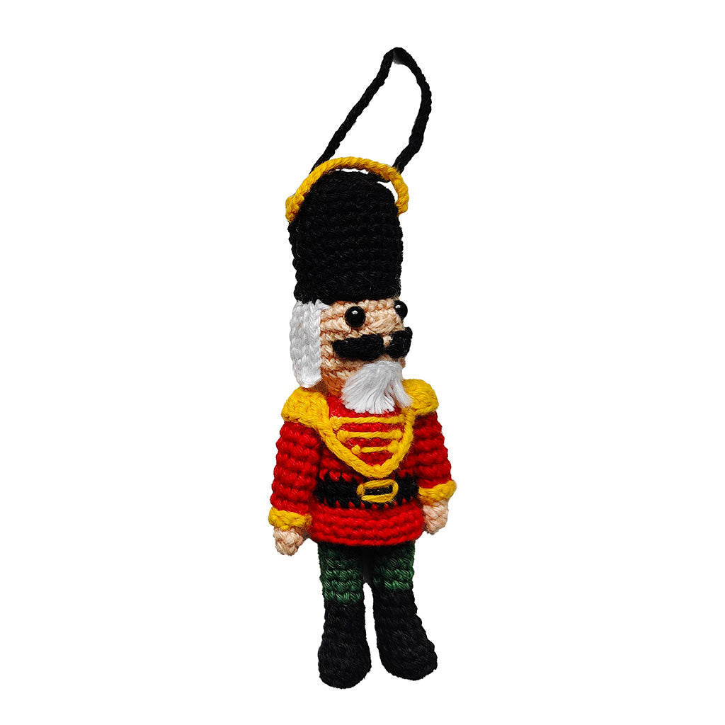 Crocheted nutcracker with a red jacket and black hat on a white background