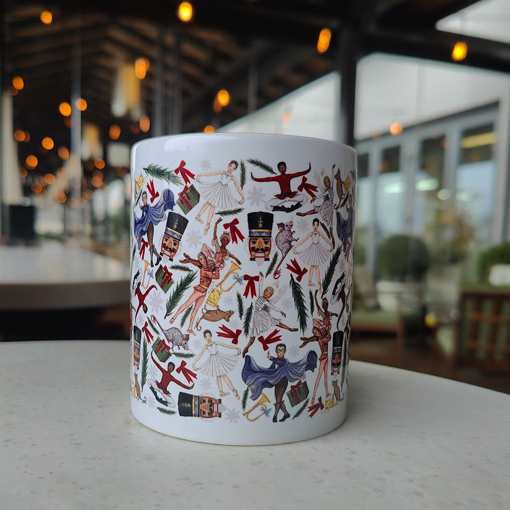 White mug with colourful Nutcracker illustrations on a blurred indoor background