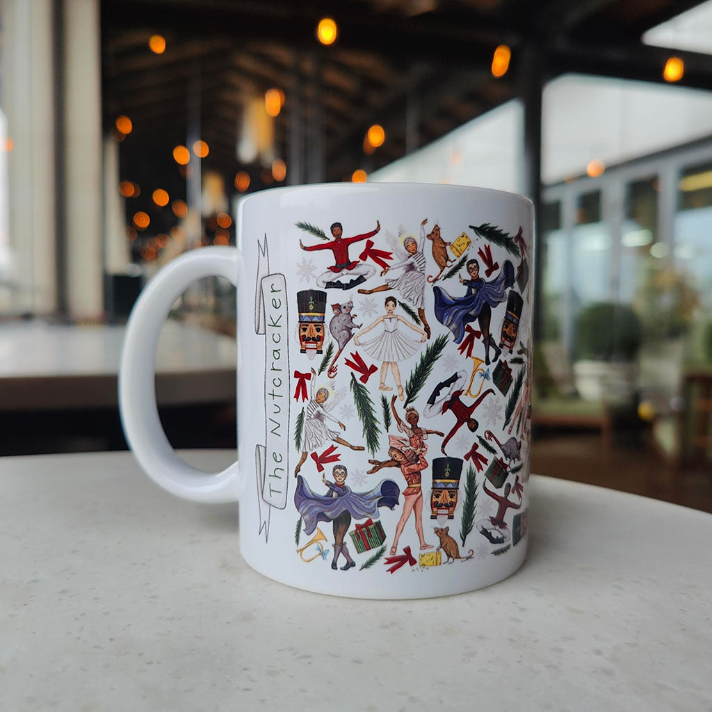 White mug with colourful illustrations of &#39;The Nutcracker&#39; on a blurred indoor background