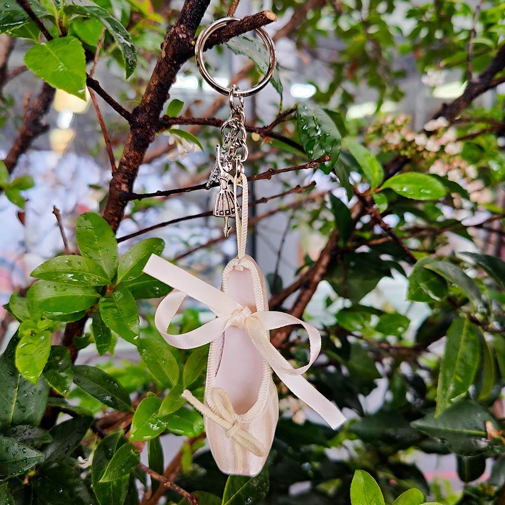 Ballet Shoe Keying in light gold with clara and snowflake charms hanging on a tree branch