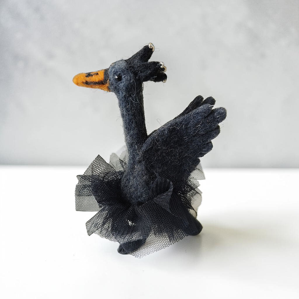 Black swan ballet decoration with orange beak and black tutu on a white background