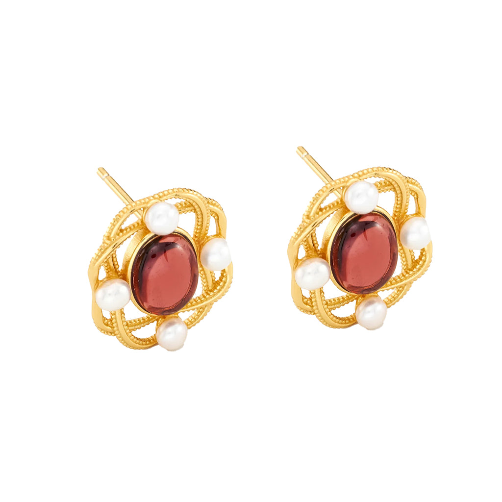 A pair of gold filigree stud earrings featuring oval dark red gemstones and small white pearls, shown on a plain white background.