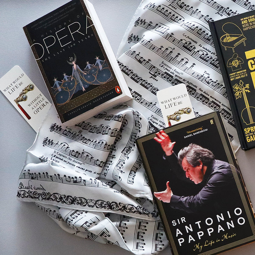 Opera books and music score scarf on a gray surface
