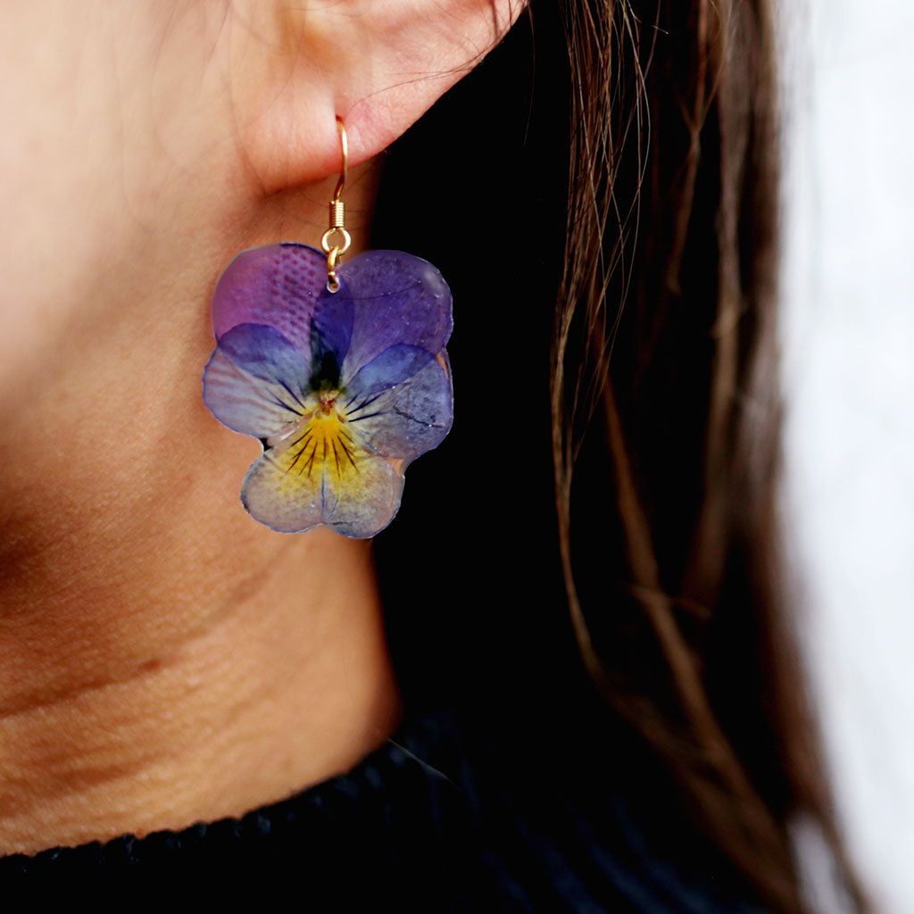 Purple and yellow flower-shaped earrings on a white background