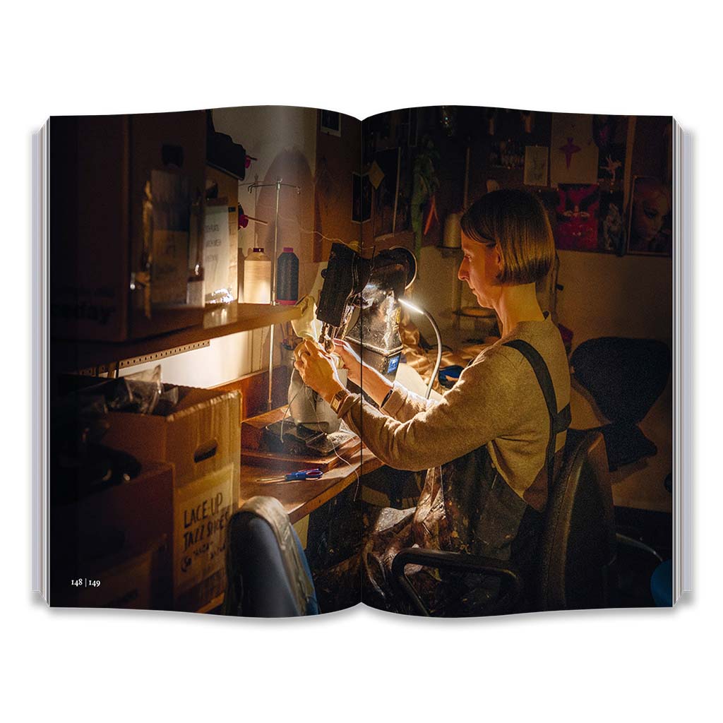Open book showing a person working on a sewing machine in a dimly lit room.