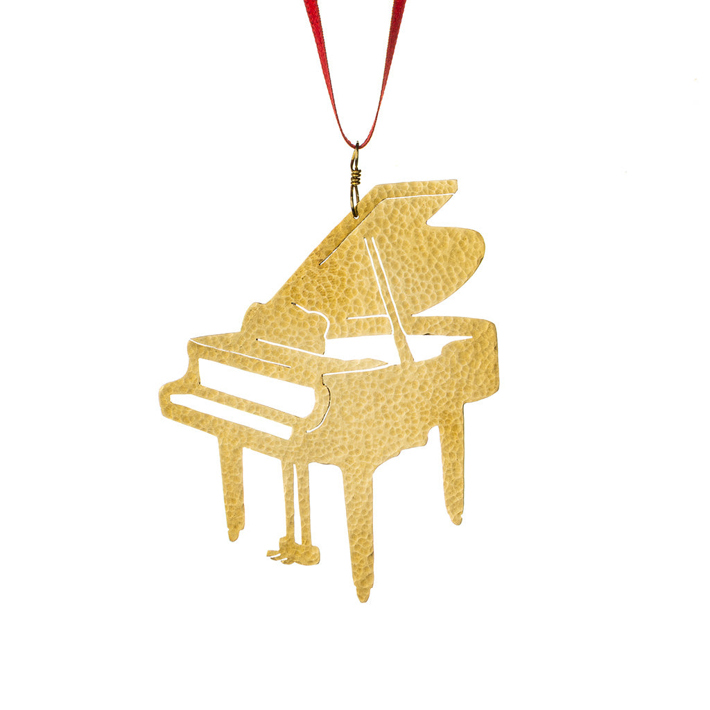 A brass ornament shaped like a grand piano, featuring a textured pattern and hanging from a red ribbon on a white background.