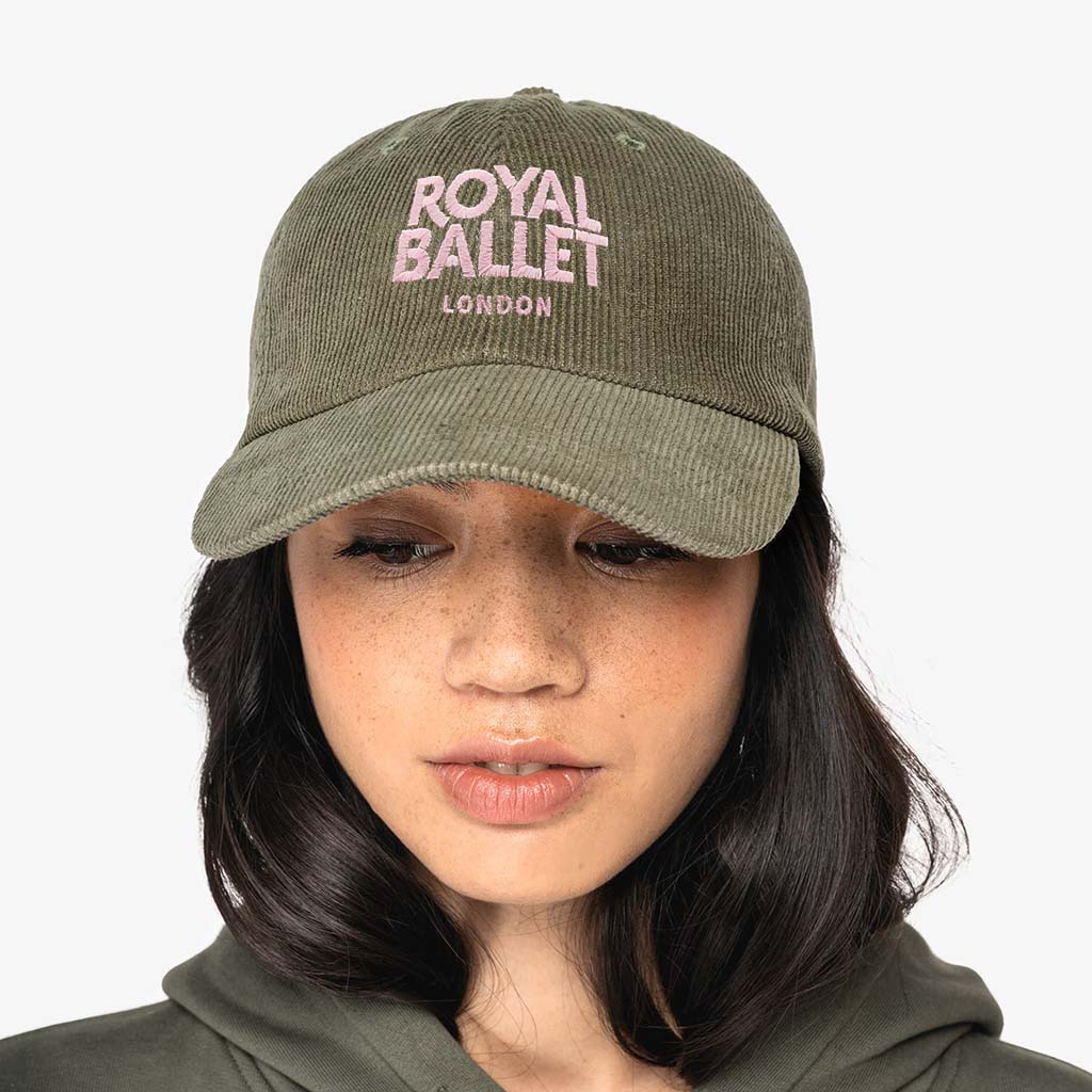 Person wearing a green cap with pink woven 'Royal Ballet London' text on a white background