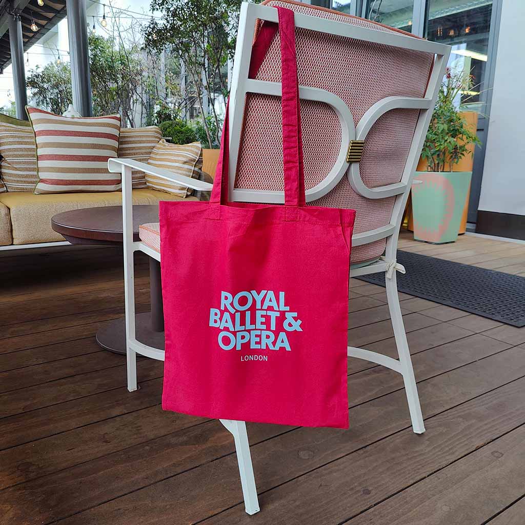 Cranberry tote bag with 'Royal Ballet &amp; Opera London' text on a chair on the terrace.