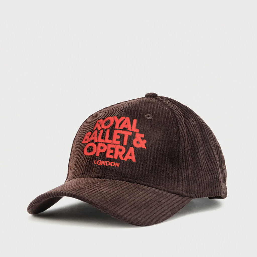 A dark brown corduroy baseball cap featuring 'ROYAL BALLET &amp; OPERA LONDON' embroidered in bright red on the front, shown against a light grey background.