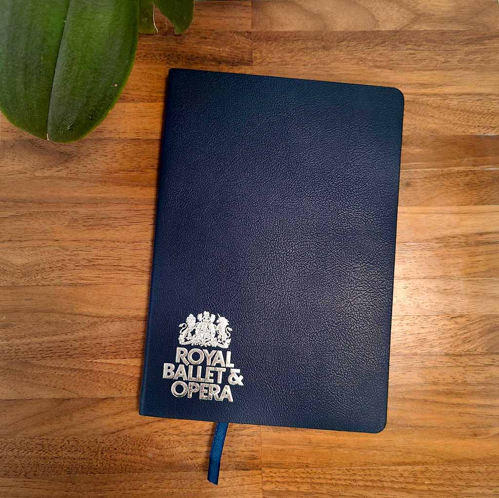 Navy Royal Ballet and Opera Notebook on wooden table with plant