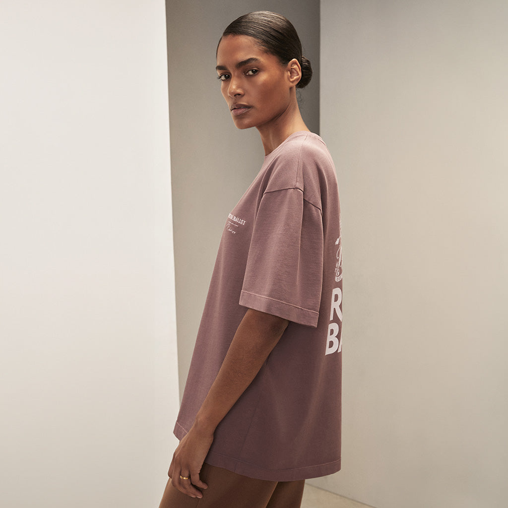 Person wearing a rose pink t-shirt with &#39;Royal Ballet Reiss&#39; logo