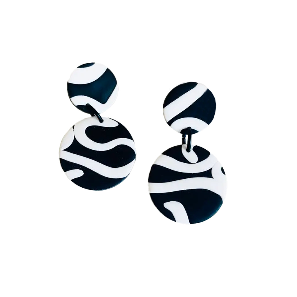 White and  black round abstract earrings featuring two clay discs against a white background