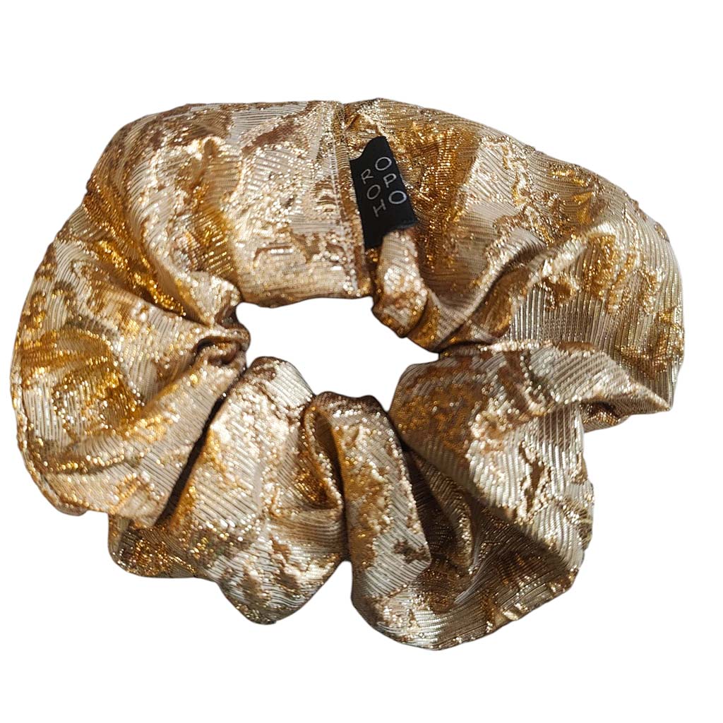 Gold scrunchie with a brand tag on a white background