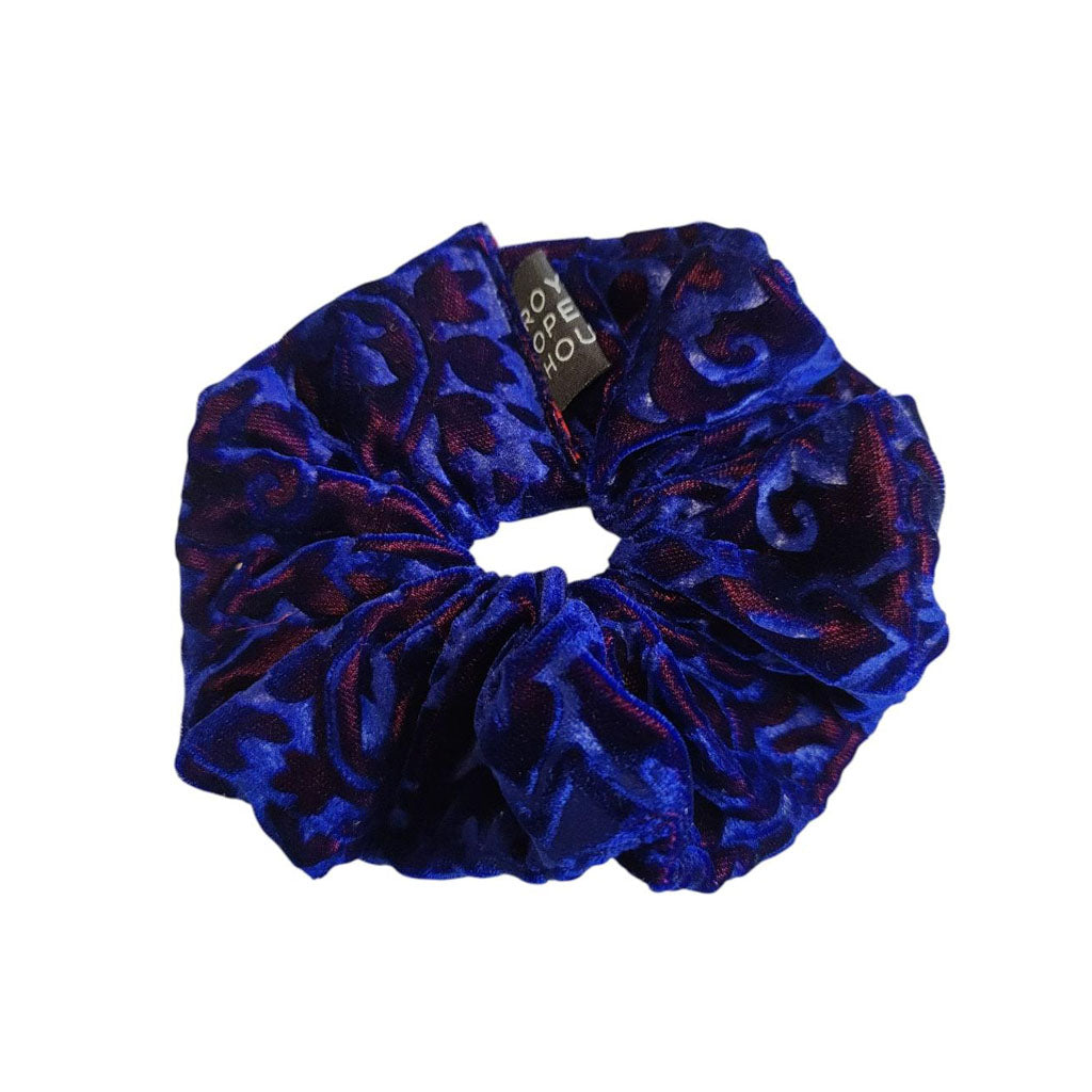 Blue velvet scrunchie with a brand tag on a white background