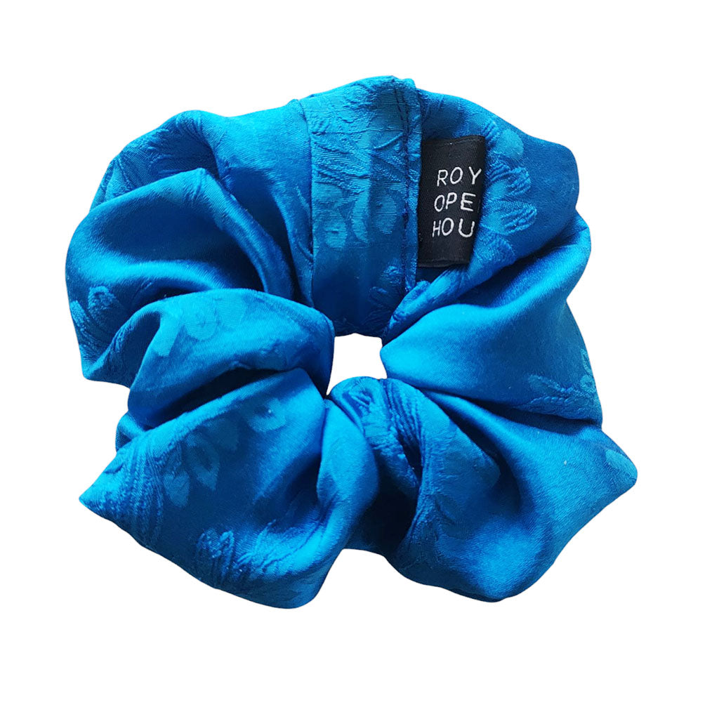Blue scrunchie with a brand label on a white background